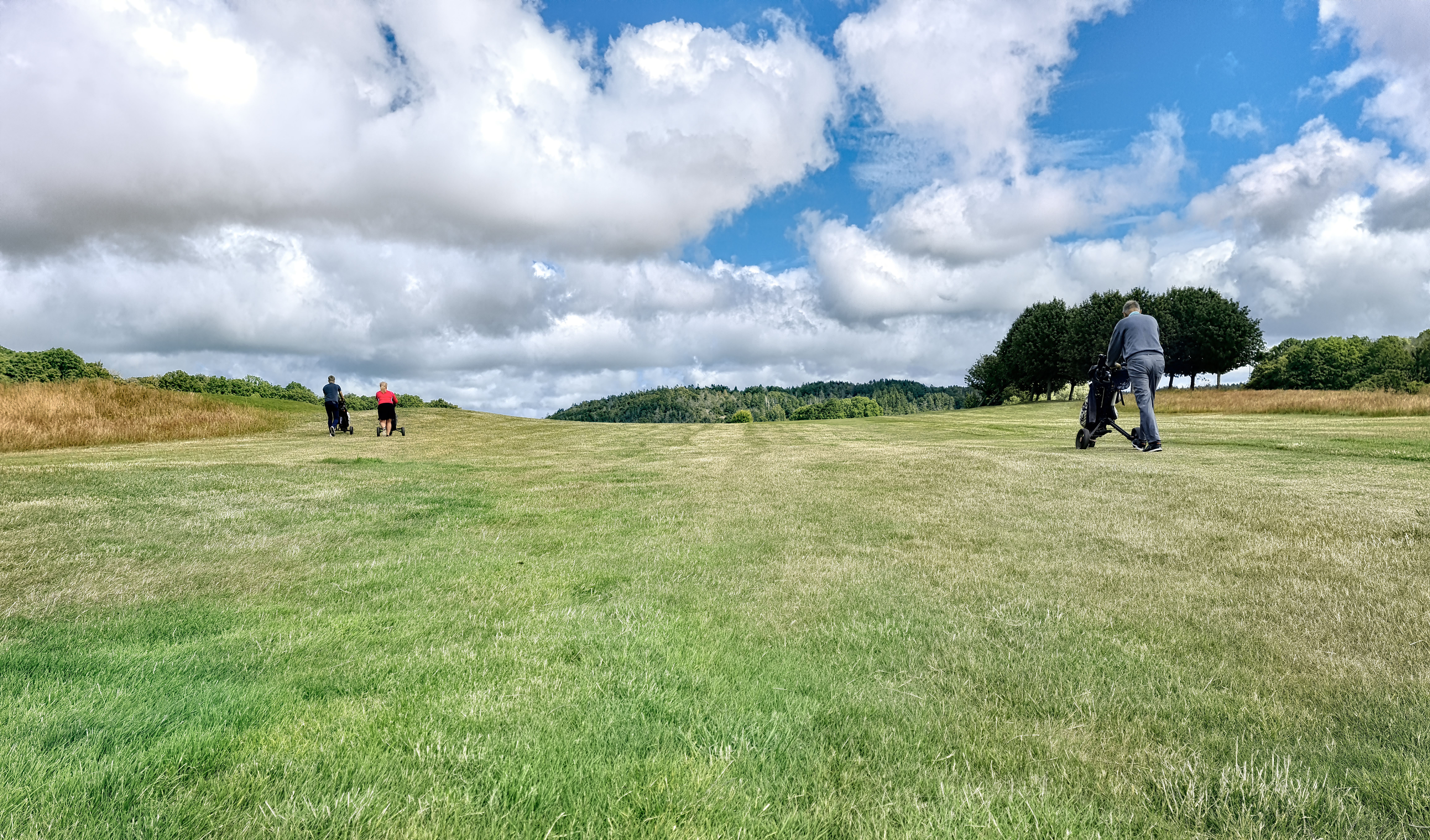 Golfers on green course under dramatic sky in Ireland