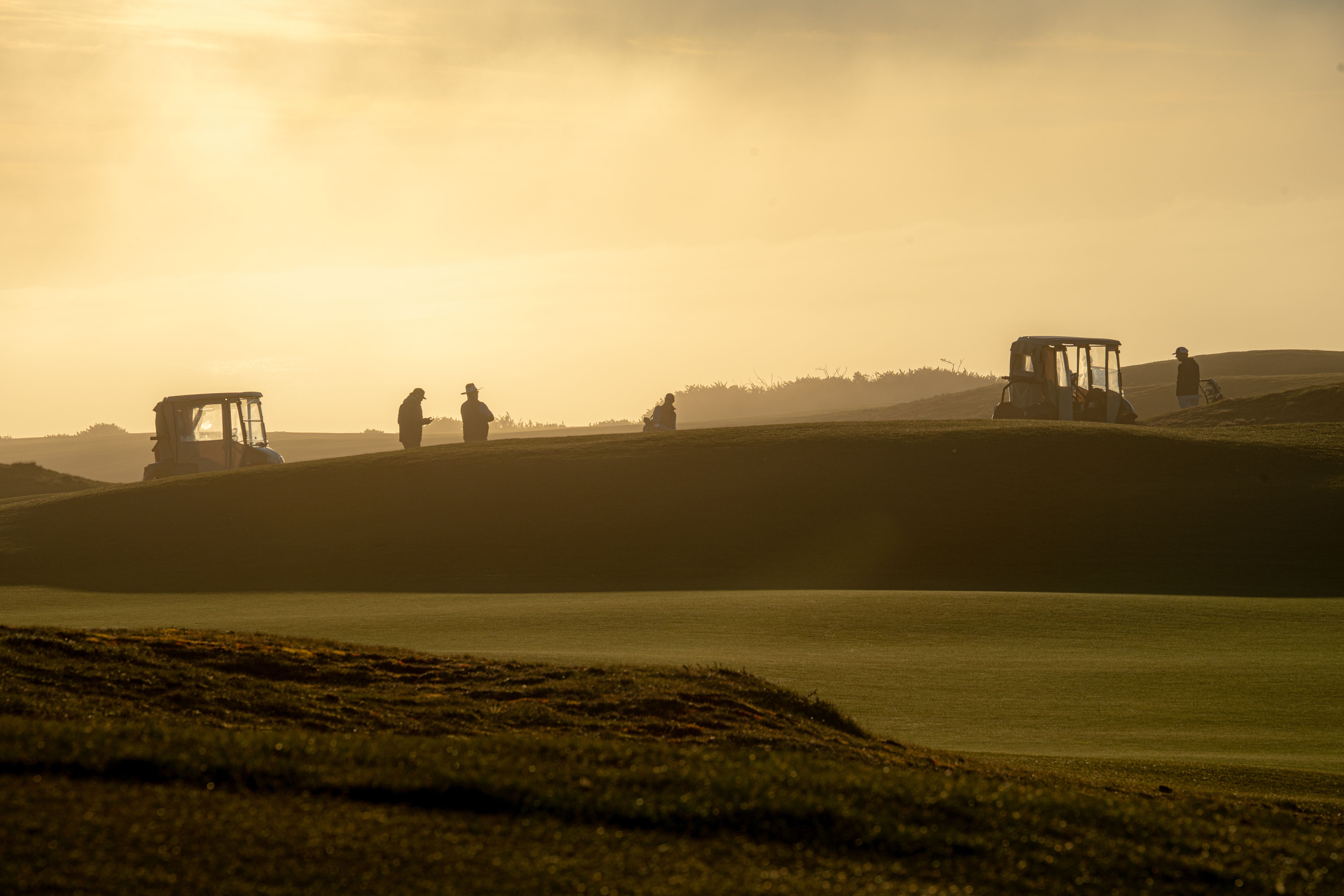 Golf course at golden hour with players in the distance